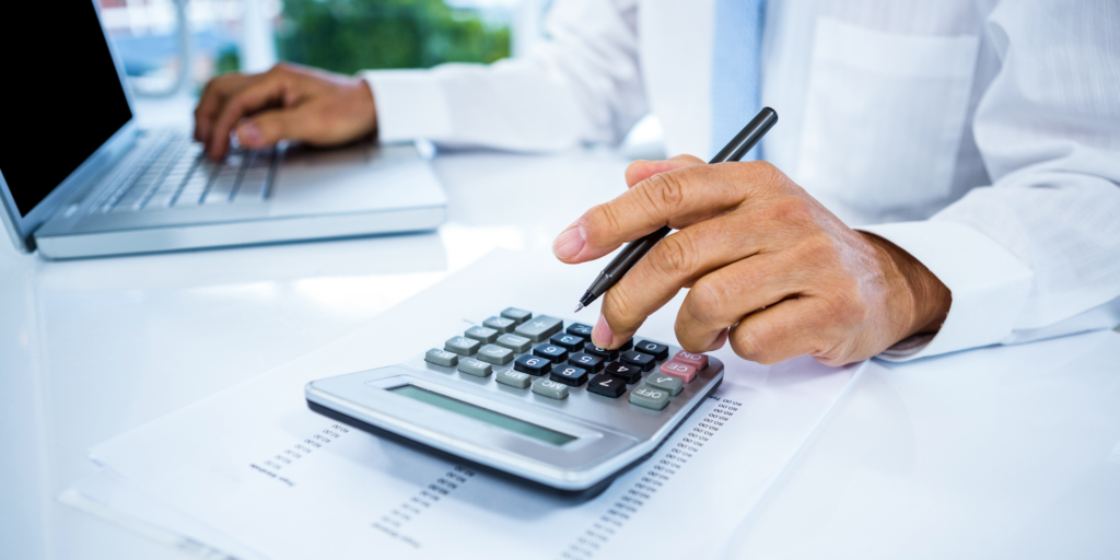 Professional calculating tax benefits for the small benefit exemption scheme on a calculator with corporate tax forms and a laptop in the background.