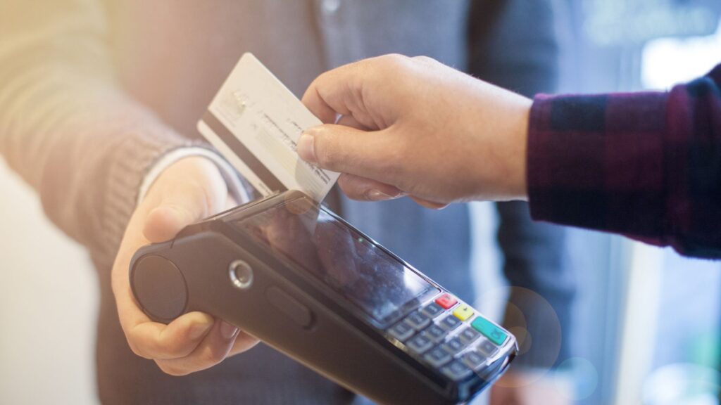 Image shows a SWIRL Prepaid Mastercard Customer topping up via their local payzone retailer in ireland