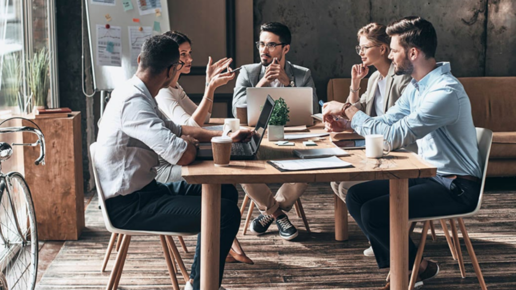 A group of colleagues engaged in a meeting around a table discussing human resource matters.